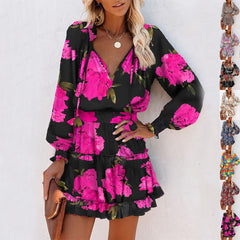 Woman wearing a black long sleeve mini dress with bright pink floral print, puffed sleeves, and a fitted waist, accessorized with a brown clutch and necklace.