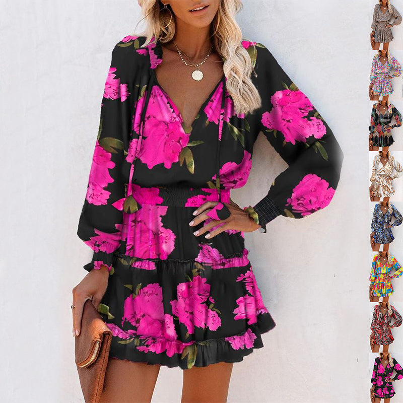 Woman wearing a black long sleeve mini dress with bright pink floral print, puffed sleeves, and a fitted waist, accessorized with a brown clutch and necklace.