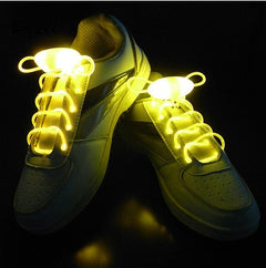 White sneakers with ultra-bright yellow LED glowing shoelaces illuminated in the dark, designed for night running and parties.