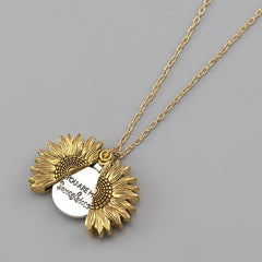Gold sunflower locket necklace with a hidden engraved message inside, displayed on a delicate gold chain against a neutral background.