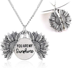 Silver sunflower locket necklace with detailed petals, featuring a hidden message inside that reads "You Are My Sunshine," displayed open and closed on a white background.