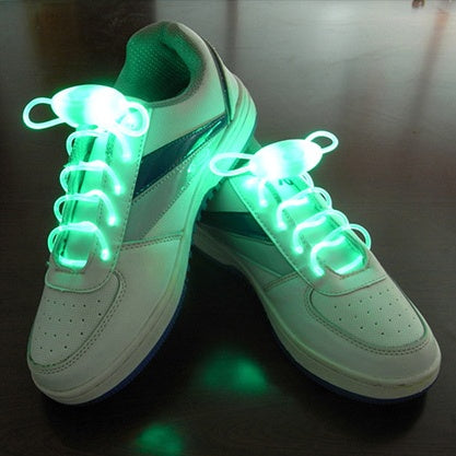 White sneakers with glowing green LED light up shoelaces designed for night running, parties, and kids’ shoes, showcasing bright waterproof glowing shoe strings.