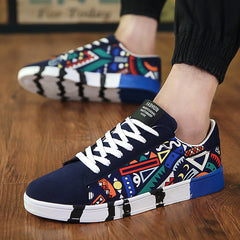 Men's low-top canvas sneakers featuring a vibrant multicolor geometric urban print with black and blue accents and white laces, offering breathable comfort and trendy style.