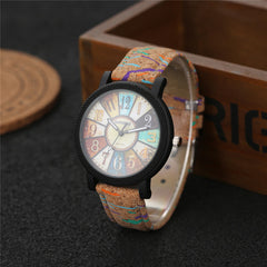 Vintage-inspired women's wristwatch featuring a multicolor boho dial and a textured retro leather strap, displayed on a dark surface beside a wooden box.