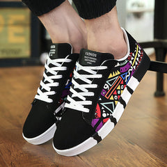 Men's low-top sneakers featuring a vibrant multicolor geometric graffiti print on black canvas with white laces and a comfortable breathable design.