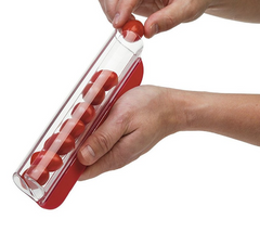 Hands using a red and clear kitchen slicer to cut cherry tomatoes evenly, demonstrating a simple and precise way to slice small fruits or vegetables.