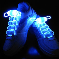 Pair of white sneakers with ultra-bright blue LED light-up shoelaces glowing vividly in a dark setting, highlighting waterproof glowing shoe strings for night use.