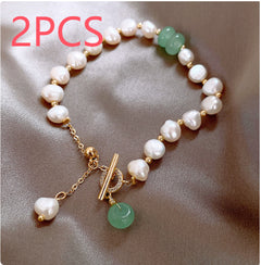 Delicate adjustable bracelet featuring irregular white freshwater pearls, small gold spacer beads, and a green jade charm on a satin background.