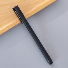 Sleek black pen with a matte finish resting on a wooden surface, designed for smooth and precise writing in an office setting.