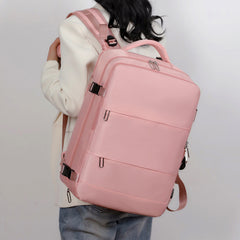 Woman wearing a stylish large pink travel backpack with multiple compartments and padded straps, suitable for laptops with USB charging port and shoe storage.