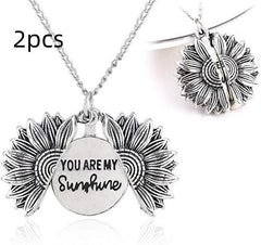 Two silver sunflower pendants, one shown closed and the other open revealing the hidden message "You Are My Sunshine," both hanging on delicate chains against a white background.
