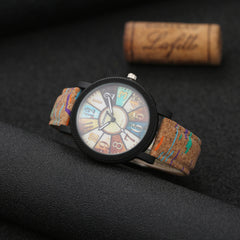 Vintage-style women’s wristwatch with a multicolor boho dial and a textured leather strap, displayed on a dark textured surface with a wine cork nearby.