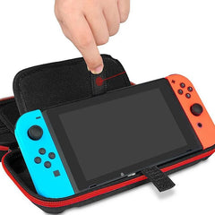 Hand placing a portable handheld gaming console into a black and red shockproof carrying case designed for secure storage and travel protection.