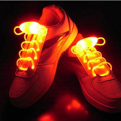 Pair of white sneakers featuring glowing red LED light up shoelaces designed for night safety, parties, and kids' footwear vibrant illumination.