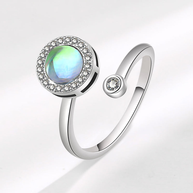 Adjustable white gold plated ring with a rotatable design featuring a central iridescent stone surrounded by small clear crystals, elegant and eye-catching.