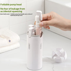 Hand placing a refillable travel dispenser bottle with foldable pump head into a sleek white leak-proof toiletry holder on a bathroom counter with folded towels nearby.