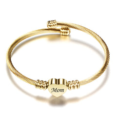 Gold-toned textured cable bracelet featuring a heart-shaped charm engraved with the word "Mom," ideal as a sentimental personalized gift for Mother's Day.