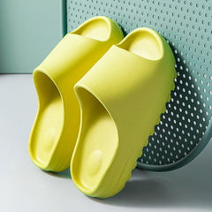 Pair of bright yellow lightweight platform beach sandals with thick cushioned soles resting against a perforated teal chair, designed for all-day comfort.