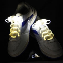 Pair of white sneakers with glowing waterproof LED shoelaces emitting bright white light, ideal for night running, parties, and kids' footwear safety.