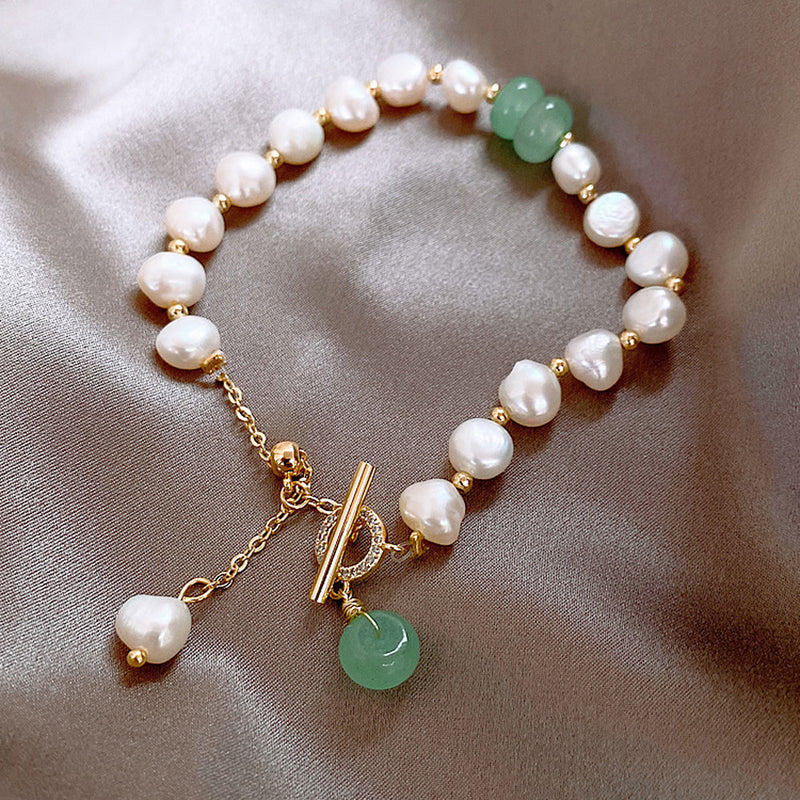 Delicate bracelet featuring irregular white freshwater pearls paired with smooth green jade beads and gold accents on a satin background, highlighting elegant adjustable design.