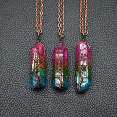 Three handcrafted crystal pendants with rainbow aura quartz in vibrant pink, green, and blue hues, each wrapped with copper wire in a tree of life design on copper chains.