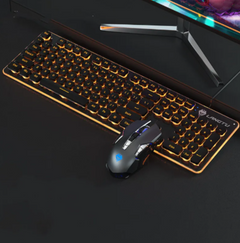 Backlit gaming keyboard with 104 keys illuminated by orange LED lighting, accompanied by a sleek gaming mouse on a black desk beneath a computer monitor.