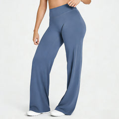 Woman wearing blue high-waisted, straight leg yoga pants made from buttery soft fabric, styled for lounge or fitness activities, paired with white sneakers.