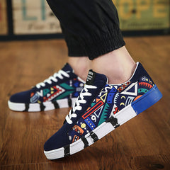 Men's low-top canvas sneakers featuring a vibrant multicolor geometric graffiti design with breathable material and a contrasting blue and white sole.