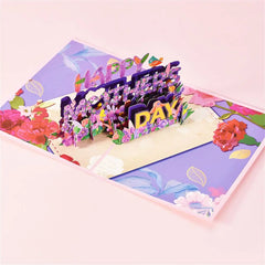 3D pop-up Mother's Day card featuring a colorful floral bouquet and layered "Happy Mother's Day" text, set against a pastel purple floral background.