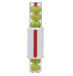Handheld fruit slicer with green grapes inside, featuring a white handle with a red grip strip designed for easy cutting of tomatoes and vegetables.