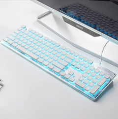 White wired luminous keyboard with blue LED backlighting placed on a clean white desk next to a monitor, designed for home and office use.