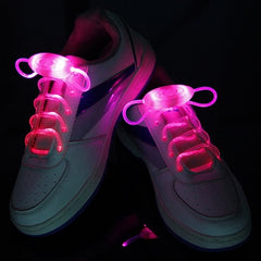 White sneakers with vibrant pink glowing LED light-up shoelaces designed for visibility during night running, parties, and kids’ activities.