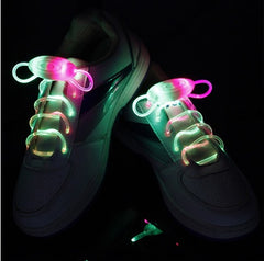 White sneakers with waterproof multicolor glowing LED shoelaces lit up in green and pink, suitable for night running, parties, and kids’ shoes.