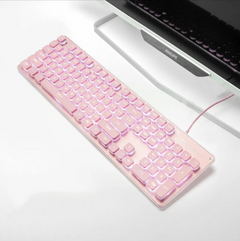 Pink USB wired gaming keyboard with white backlit keys connected to a computer monitor on a white desk, designed for home and office use.