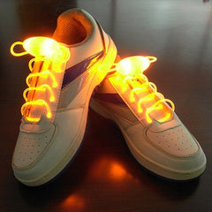 Pair of white sneakers with glowing bright orange LED light-up shoelaces, designed for nighttime visibility and stylish wear at parties or night running.