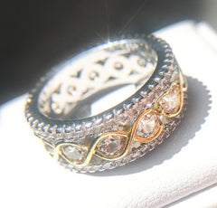 Close-up of a two-tone gold infinity band ring with round cut cubic zirconia stones, featuring a wide multi-row stackable design for women’s anniversary or wedding gifts.