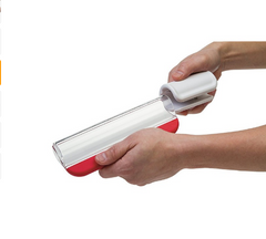 Hands holding a handheld fruit slicer with a white handle and red base, designed for evenly slicing tomatoes and vegetables with precision.