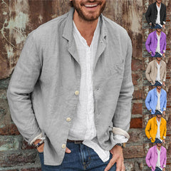 Man wearing a slim fit casual blazer made of lightweight cotton and linen in a soft beige color, paired with a white shirt and blue jeans, standing against a rustic brick wall.