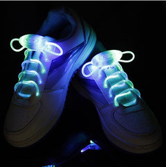 Pair of white sneakers with ultra-bright LED green and blue glowing waterproof shoelaces, illuminated for night running, parties, and kids' shoes.