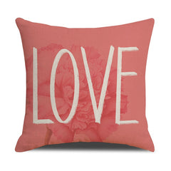 Coral pink velvet throw pillow with large white "LOVE" text and subtle floral design, soft decorative accent for sofa or bedroom, ideal for heartfelt gifts.