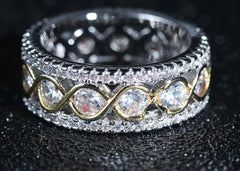 Close-up of a two-tone gold and silver infinity band ring featuring round cut cubic zirconia stones in a wide, multi-row design, ideal as an elegant anniversary gift.
