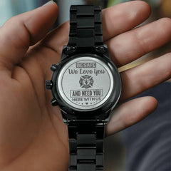 Charcoal black men's chronograph watch with engraved heartfelt message for a firefighter, held in hand, featuring a metal link band.