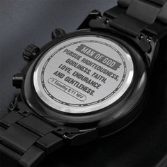 Close-up of the back of a men's black chronograph watch featuring an engraved scripture from 1 Timothy 6:11 emphasizing faith, righteousness, and gentleness.