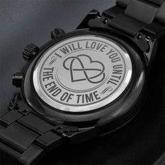 Close-up of a black men's watch with a metal back engraved with two interlocking hearts and the phrase "I will love you until the end of time," highlighting a sentimental personalized gift.