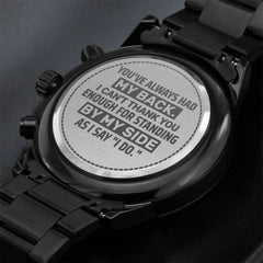 Close-up of the engraved back of a black chronograph men's watch with a heartfelt message thanking a groomsman for support, highlighting a personalized sentimental gift.