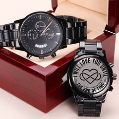 Black chronograph men's watch with metal link band displayed in a polished wooden gift box, featuring an engraved back with a heart and infinity symbol and the phrase "I will love you until the end of time