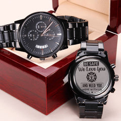 Charcoal black men's chronograph watch with engraved backplate featuring a firefighter tribute message, displayed with a matching watch inside a polished wooden gift box.