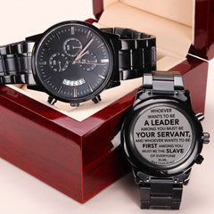 Black men's chronograph watch with metal band displayed in an open wooden box, featuring an engraved faith-based scripture message on the back cover.