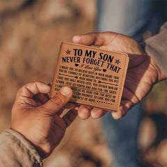 A close-up of two hands exchanging a personalized genuine leather bifold wallet engraved with a heartfelt message from a parent to their son, emphasizing encouragement and love.