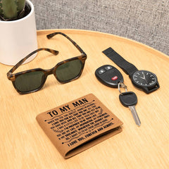 Genuine leather bifold wallet engraved with a heartfelt message, placed on a wooden surface alongside sunglasses, car keys, and a wristwatch.